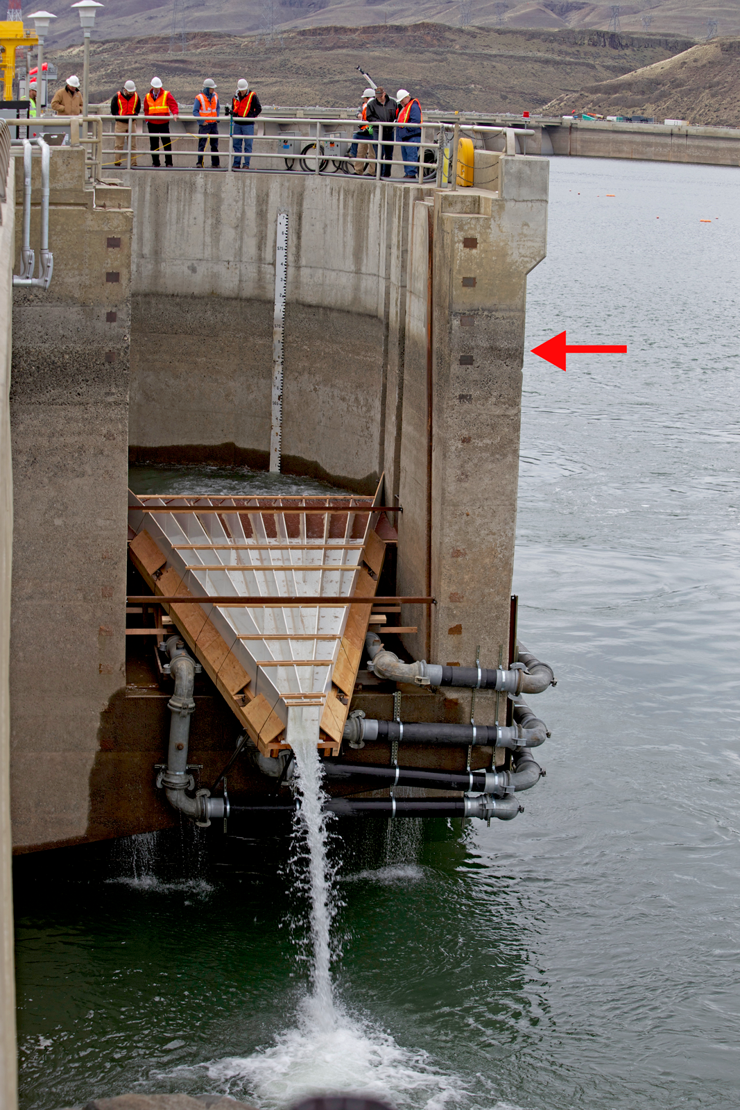 The Wanapum Dam fish ladder exit with a temporary fix that sends adult fish down a ramp into the water below. The red arrow indicates the normal reservoir level.